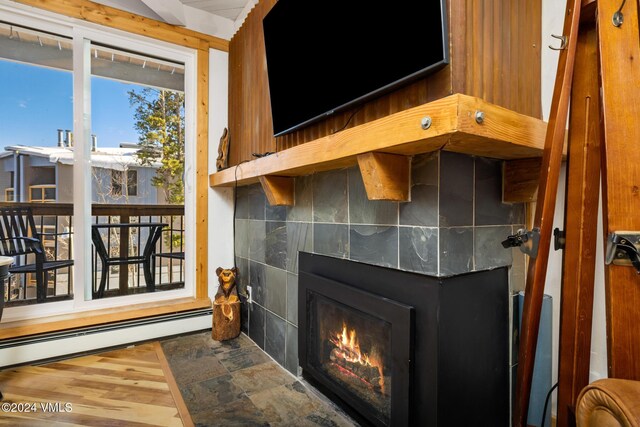 room details featuring a tile fireplace, a baseboard radiator, and hardwood / wood-style floors