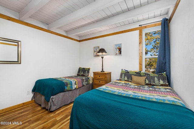 bedroom with beamed ceiling and hardwood / wood-style floors