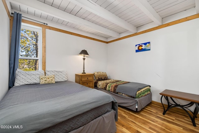 bedroom featuring beamed ceiling, wood ceiling, and light hardwood / wood-style flooring