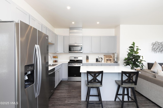 kitchen with a breakfast bar, a sink, stainless steel appliances, and light countertops