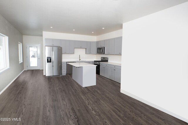 kitchen featuring gray cabinetry, sink, a kitchen island, and appliances with stainless steel finishes