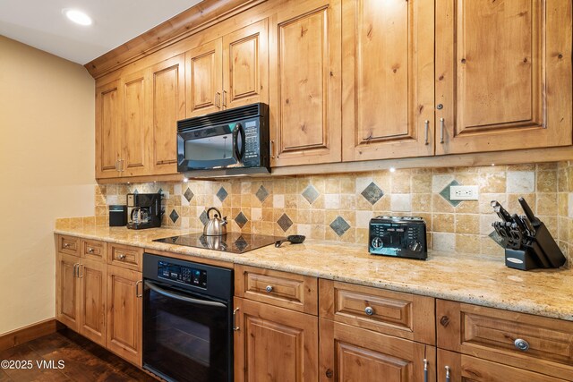 kitchen featuring light stone countertops, dark wood-type flooring, decorative backsplash, and black appliances