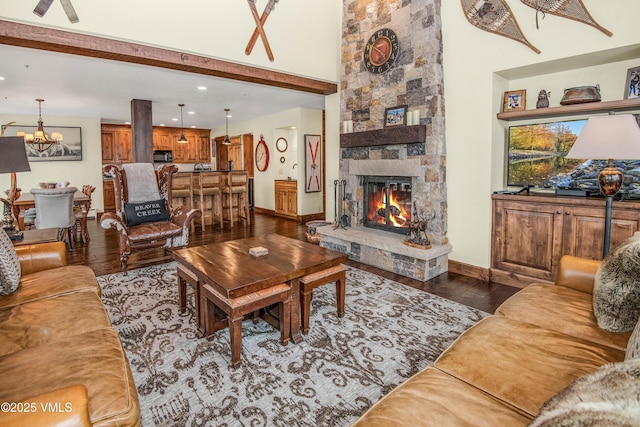 living room featuring dark hardwood / wood-style floors, an inviting chandelier, a fireplace, and a towering ceiling