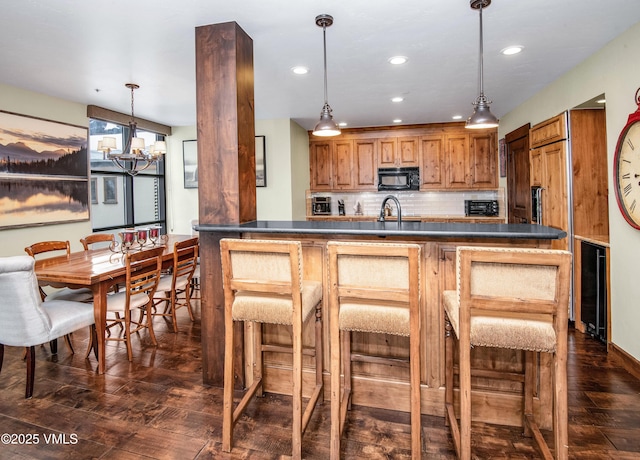 kitchen with sink, dark hardwood / wood-style flooring, a kitchen breakfast bar, pendant lighting, and backsplash