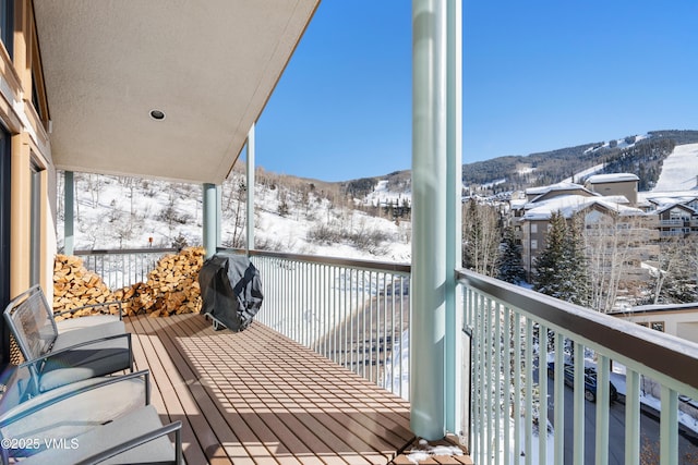 snow covered back of property with a mountain view and a grill