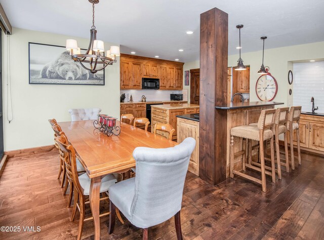 dining area with sink, a notable chandelier, and dark wood-type flooring