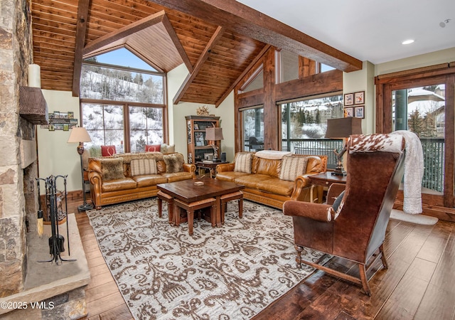 living room with high vaulted ceiling, beamed ceiling, a large fireplace, wooden ceiling, and light hardwood / wood-style flooring