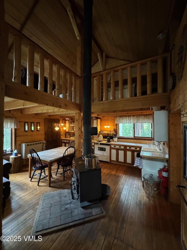 1234 6th St, Eagle, CO 81631 - dining area with wood walls, hardwood / wood-style floors, a wood stove, high vaulted ceiling, and radiator