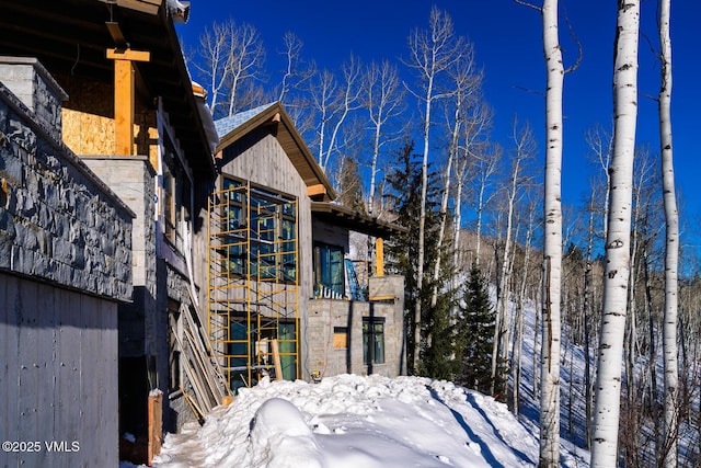 view of snow covered exterior with stone siding