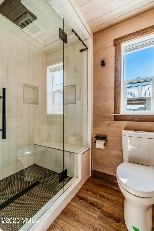 329 River Frontage Rd Unit 18, Silt, CO 81652 - bathroom featuring a stall shower, wood walls, toilet, and wood finished floors