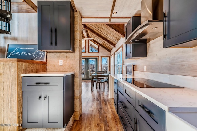 329 River Frontage Rd Unit 18, Silt, CO 81652 - kitchen with black electric stovetop, wood ceiling, wall chimney range hood, wood finished floors, and high vaulted ceiling