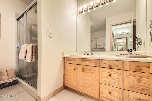 bathroom with tile patterned flooring, a shower stall, baseboards, double vanity, and a sink