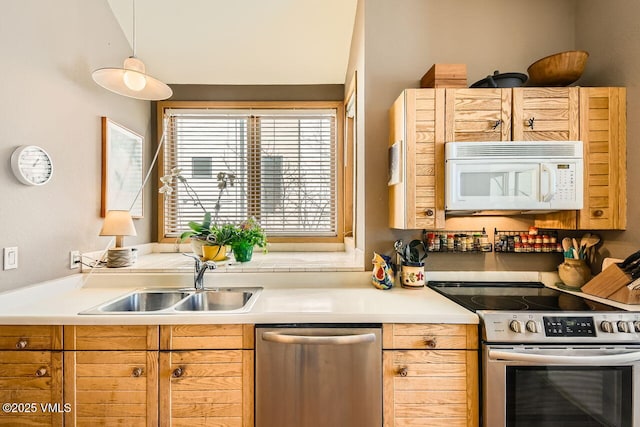 kitchen with decorative light fixtures, stainless steel appliances, light countertops, and a sink