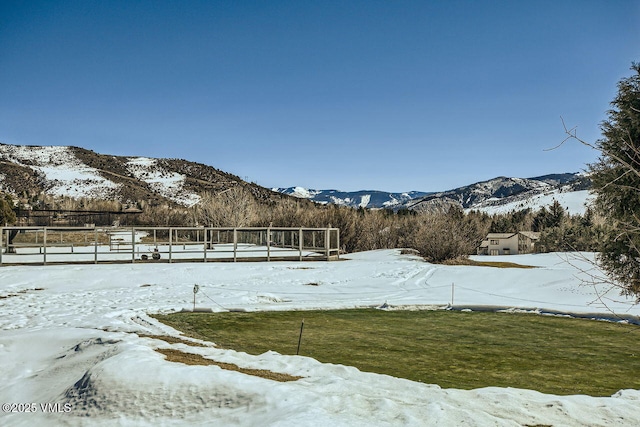 snowy yard featuring a mountain view and fence