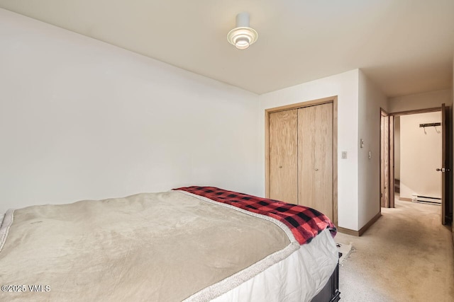 bedroom featuring a closet, light carpet, baseboard heating, and baseboards