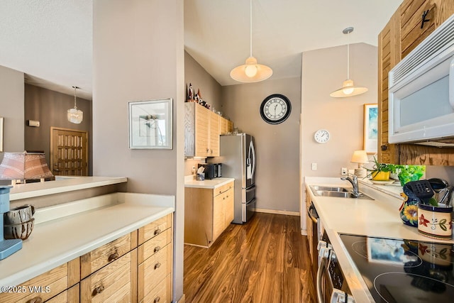 kitchen with pendant lighting, a sink, dark wood finished floors, appliances with stainless steel finishes, and light countertops