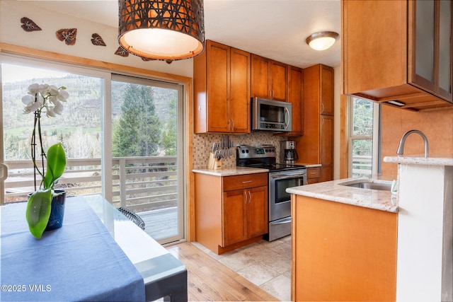 5024 Main Gore Dr S Unit 16, Vail, CO 81657 - kitchen featuring stainless steel appliances, brown cabinets, tasteful backsplash, and light stone counters