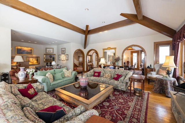 living area with beam ceiling, recessed lighting, wood finished floors, and arched walkways