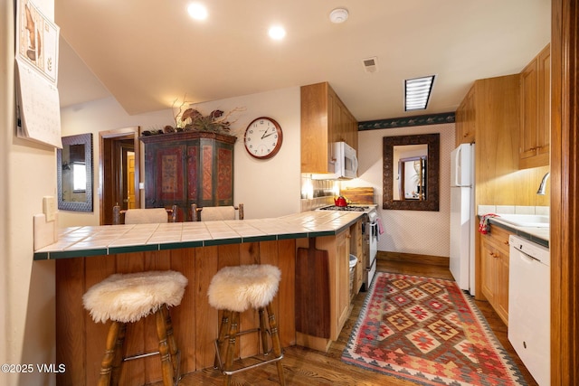 kitchen with dark wood finished floors, visible vents, white appliances, and wallpapered walls