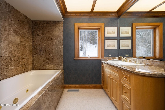 full bathroom featuring visible vents, crown molding, baseboards, tiled tub, and vanity