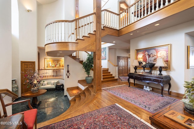 foyer with stairway, a high ceiling, baseboards, and wood finished floors