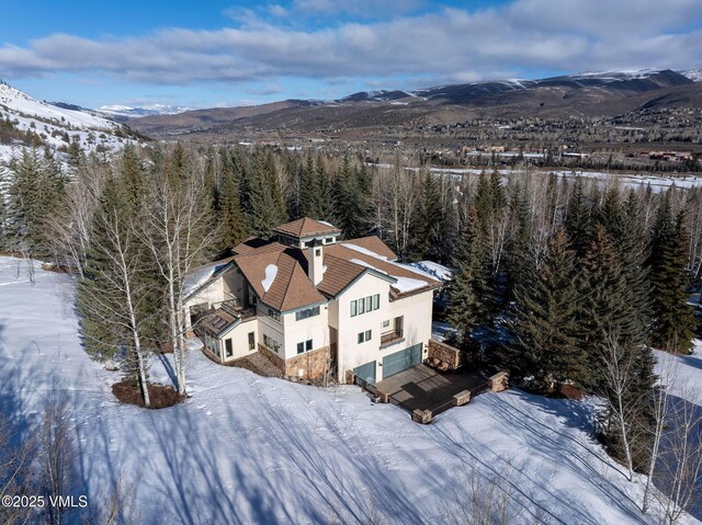 snowy aerial view with a view of trees and a mountain view