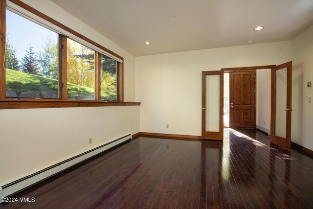 unfurnished room featuring dark hardwood / wood-style flooring and baseboard heating