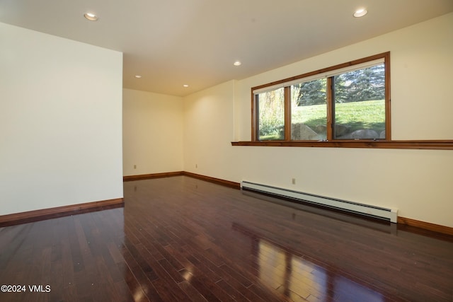 unfurnished room with dark wood-type flooring and a baseboard heating unit