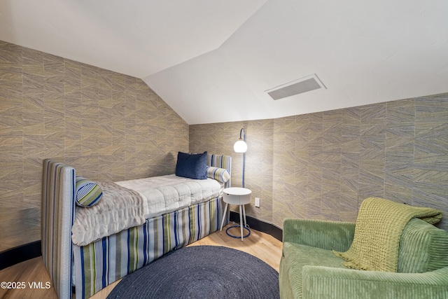 bedroom with visible vents, lofted ceiling, and wood finished floors