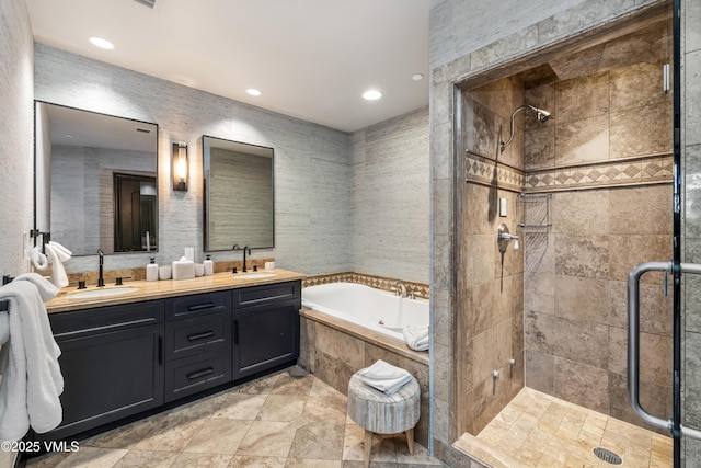 bathroom with double vanity, a stall shower, a garden tub, and a sink