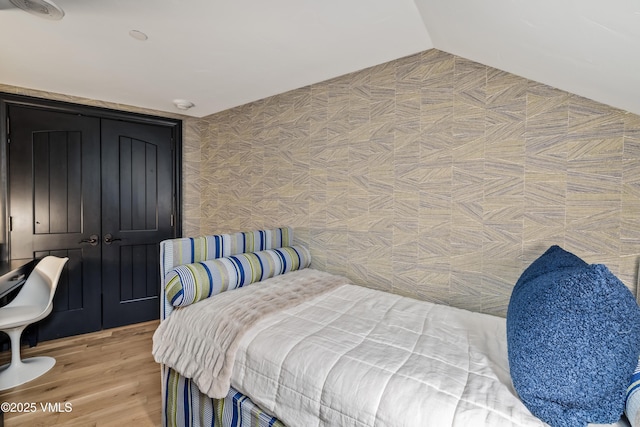 bedroom with lofted ceiling and light wood-style floors