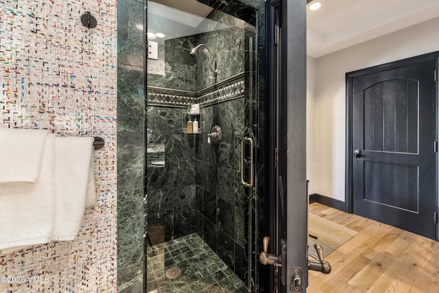 bathroom featuring baseboards, wood finished floors, and a shower stall