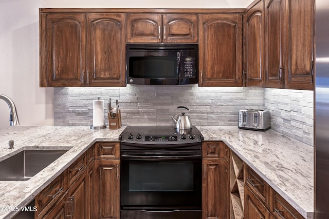 kitchen featuring light stone counters, dark brown cabinetry, a sink, backsplash, and black appliances