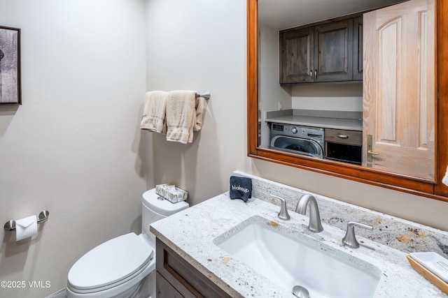 half bathroom with washer / dryer, vanity, and toilet