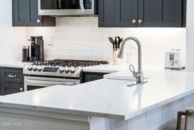 kitchen featuring tasteful backsplash, appliances with stainless steel finishes, and light stone countertops