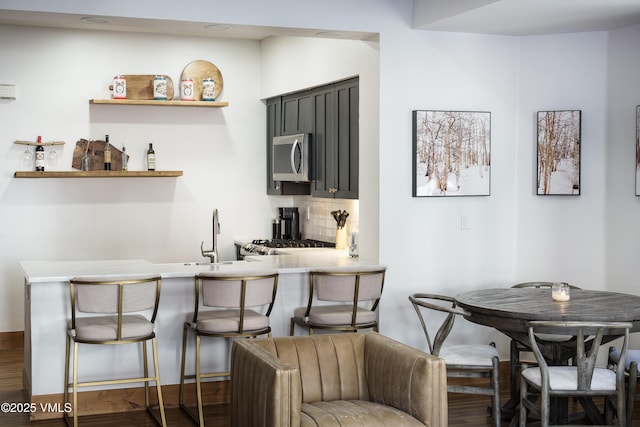 kitchen featuring dark hardwood / wood-style floors, sink, backsplash, stove, and kitchen peninsula