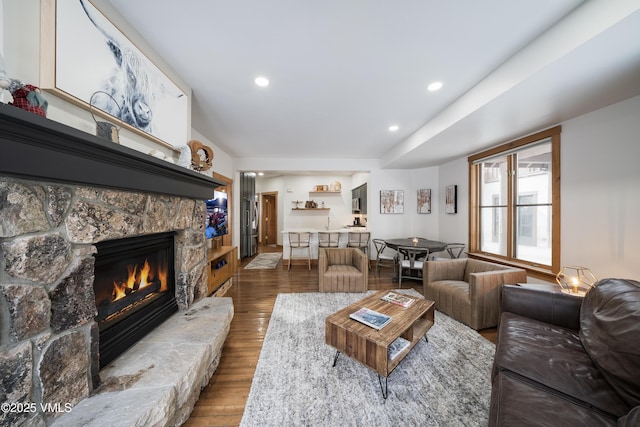 living room with wood-type flooring and a stone fireplace