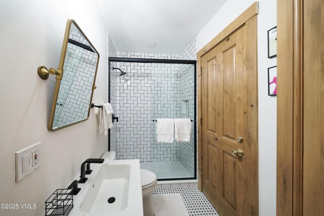 bathroom featuring toilet, a shower with shower door, and sink