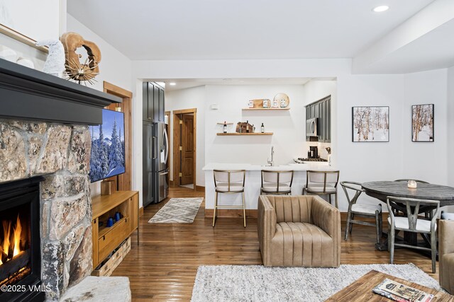 living room with dark wood-type flooring, a fireplace, and indoor wet bar