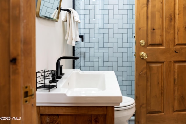 bathroom featuring sink, tile walls, and toilet