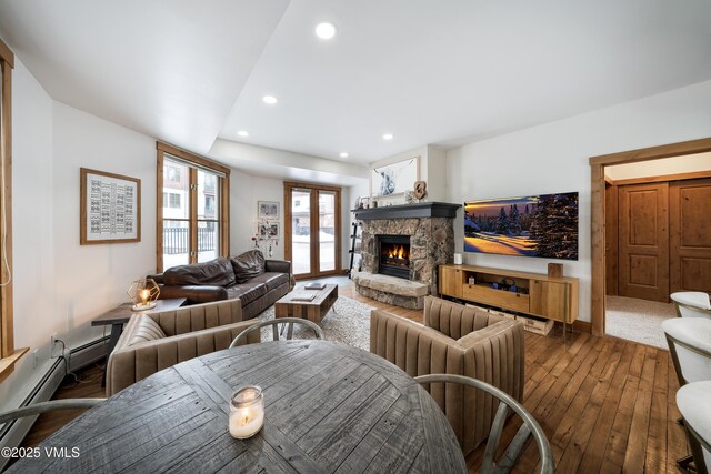 living room featuring a stone fireplace and dark wood-type flooring