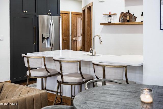 kitchen with a breakfast bar, stainless steel fridge, and kitchen peninsula