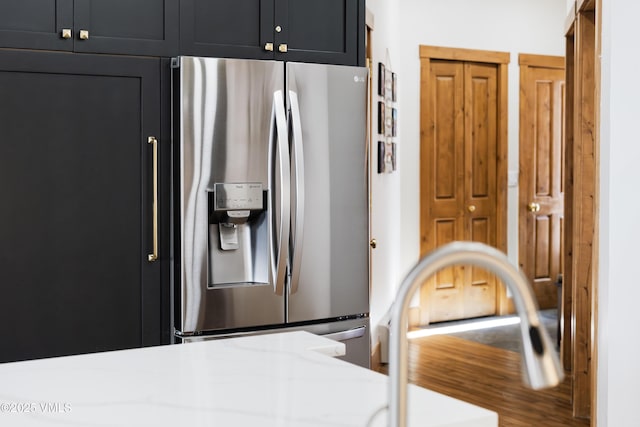 kitchen featuring stainless steel fridge and light stone counters