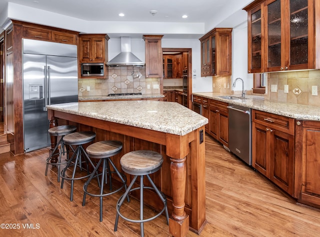 460 El Mirador Rd, Edwards, CO 81632 - kitchen with stainless steel appliances, wall chimney range hood, a sink, a center island, and light wood-type flooring