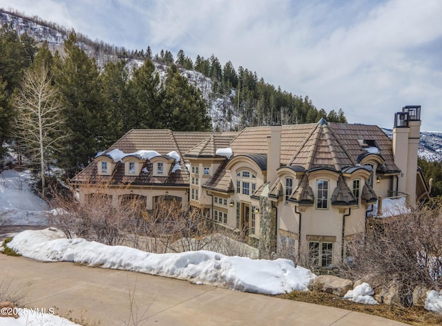 460 El Mirador Rd, Edwards, CO 81632 - snow covered back of property featuring a chimney, stucco siding, and stone siding