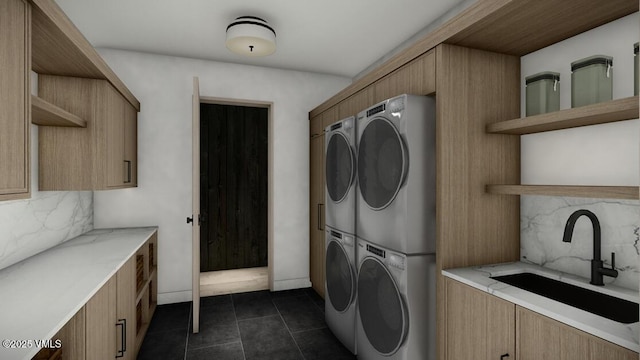 laundry area featuring stacked washer and dryer, cabinet space, a sink, and dark tile patterned floors