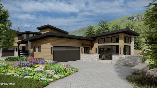 contemporary home featuring decorative driveway, an attached garage, and a mountain view