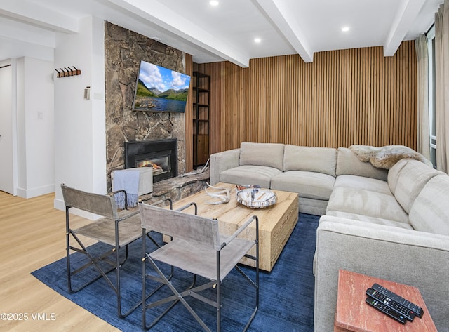 living area featuring wood finished floors, wood walls, a fireplace, beam ceiling, and recessed lighting