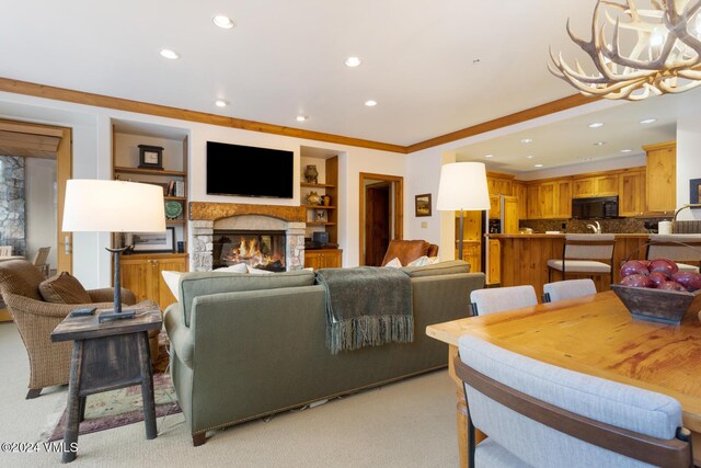 carpeted living room with crown molding, a fireplace, and a chandelier