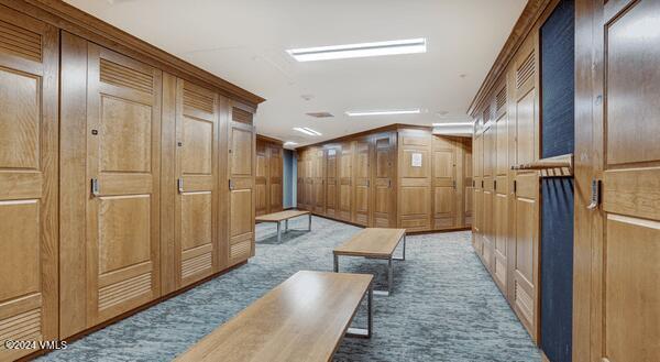 hall featuring vaulted ceiling, carpet flooring, and wood walls